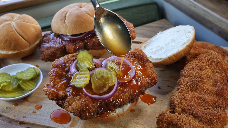 drizzling hot honey on pork tenderloin sandwich