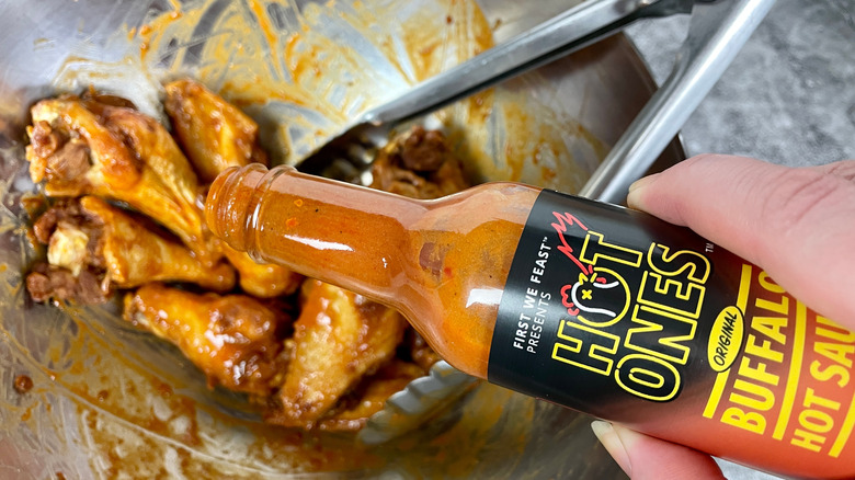 Hot Ones Original Buffalo Hot Sauce poured over wings