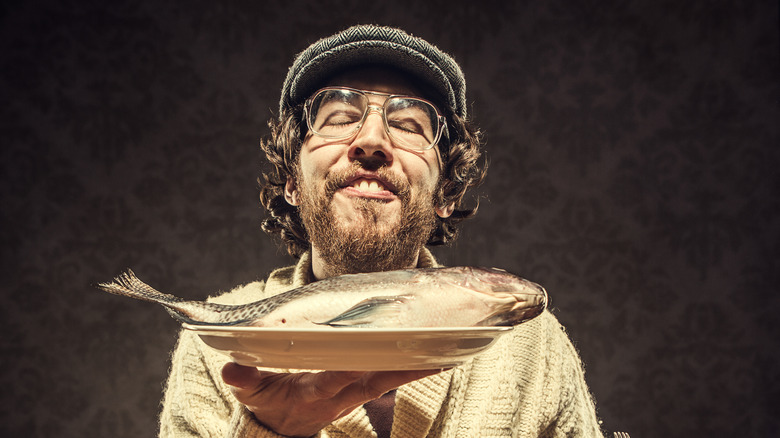 smiling man holding whole fish on platter