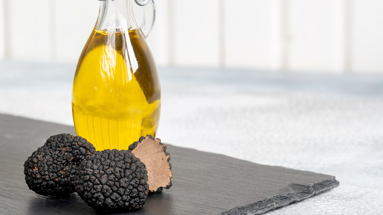 Black truffles in front of a small pitcher of oil