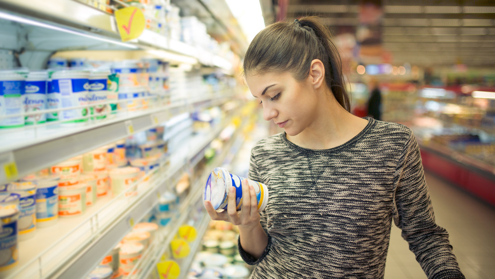 Woman checking expiration date in grocery aisle