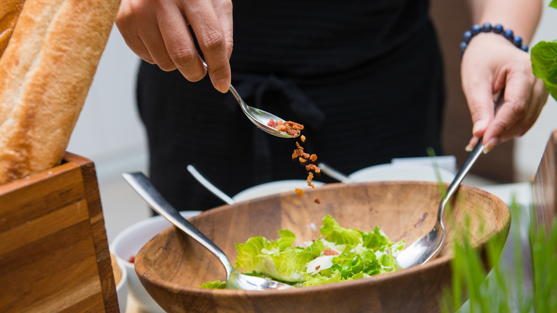 scattering bacon into caesar salad