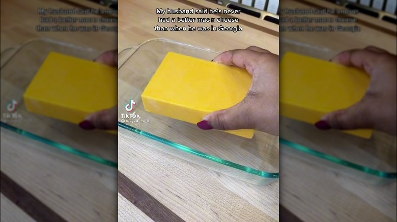 Person placing velveeta block in casserole dish