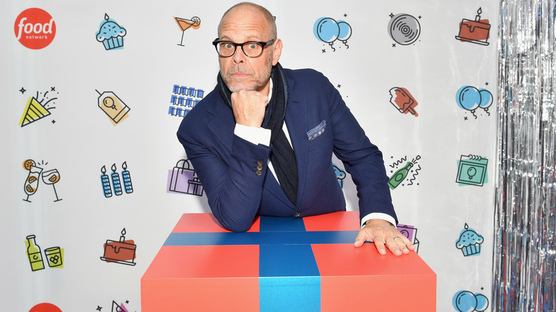 Alton Brown posing over an oversized box