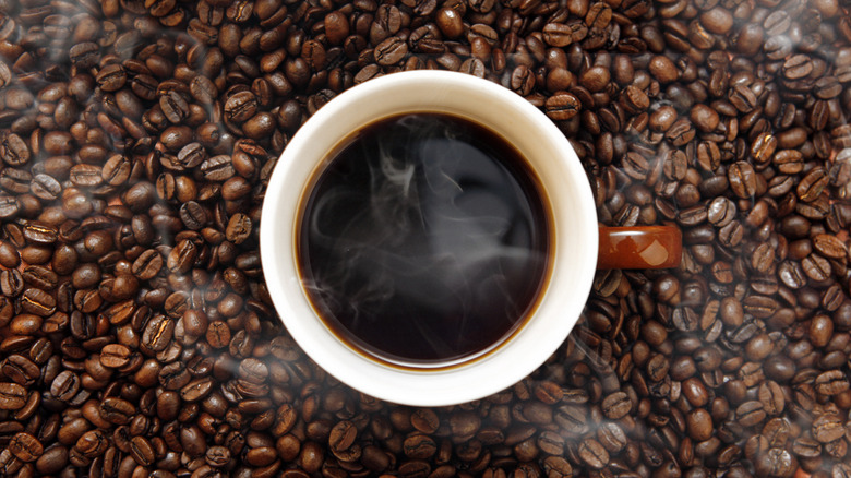 Coffee in a mug surrounded by beans