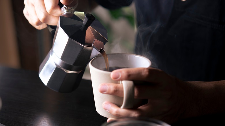 pouring a french press of coffee into a cup 