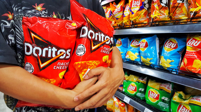 person holds bags of Doritos in grocery store