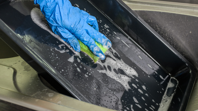 Person washing baking dish by hand