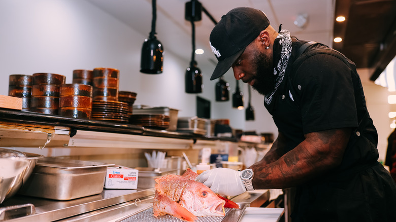 Tobias Dorzon in a black bandana cutting a fish