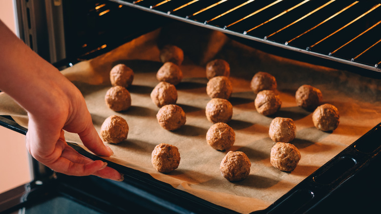 Person pulling meatballs out of the oven