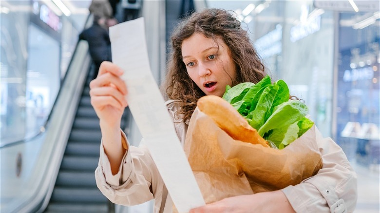 Surprised woman looking at grocery receipt