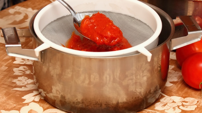 Person straining tomato mixture