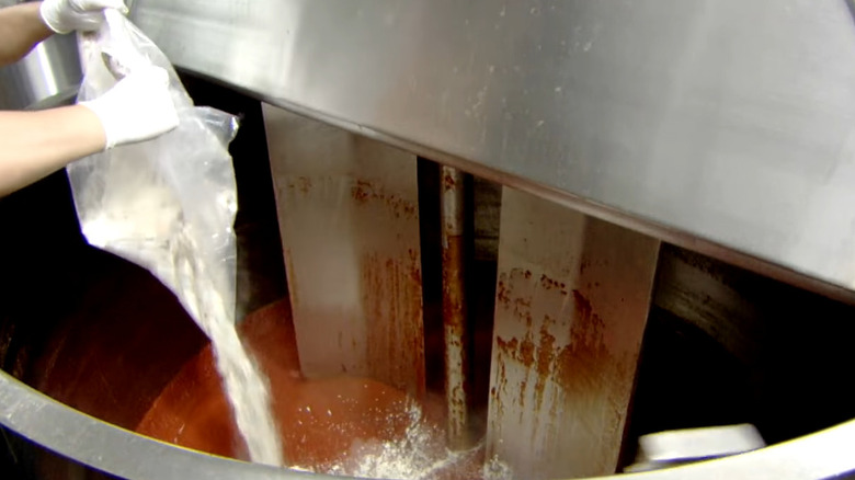 Worker adding spices during ketchup production