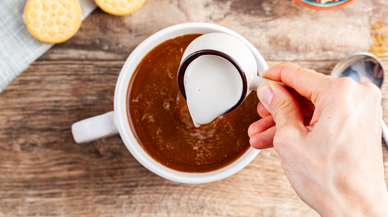 coffee in a white cup with creamer being poured in