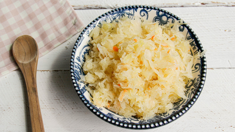 bowl of fresh sauerkraut beside wooden spoon