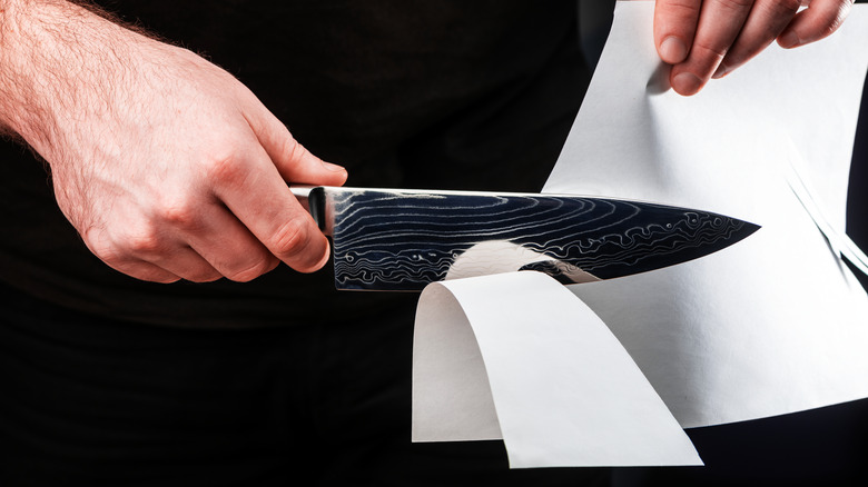 Person sharpening knife with paper