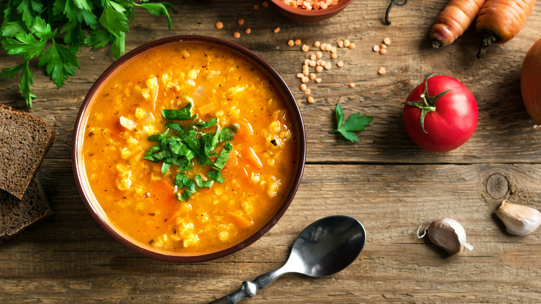 Bowl of hot soup on wooden table with spoon