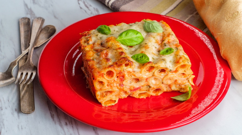 A slice of baked ziti on a red plate