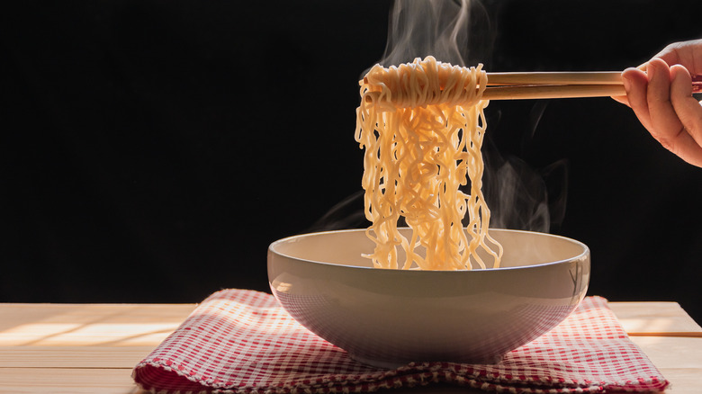 Person using chopsticks to eat ramen