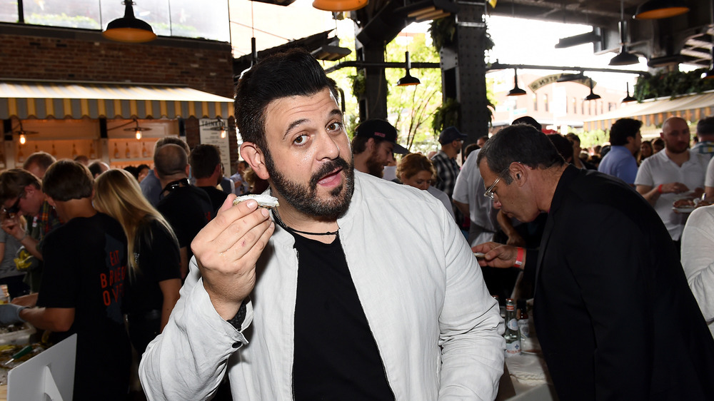 Adam Richman of Man v. Food posing with dish