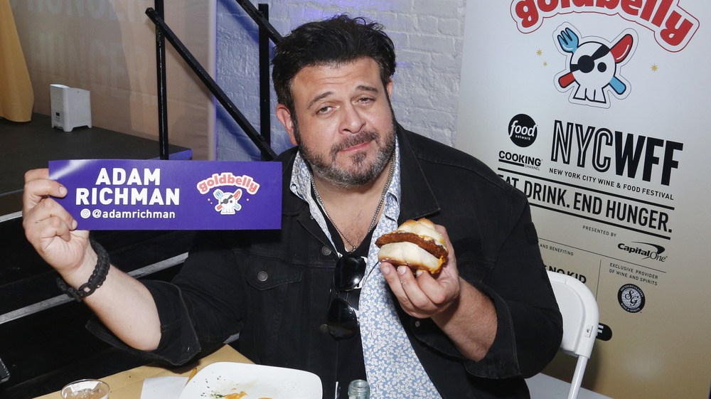 Adam Richman of Man v. Food holding a burger