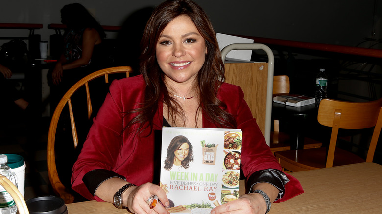 Rachael Ray smiling and holding cookbook