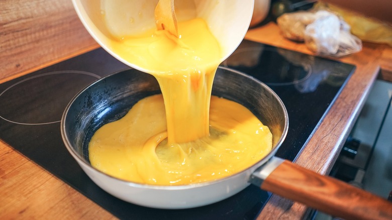 Pouring scrambled eggs into pan