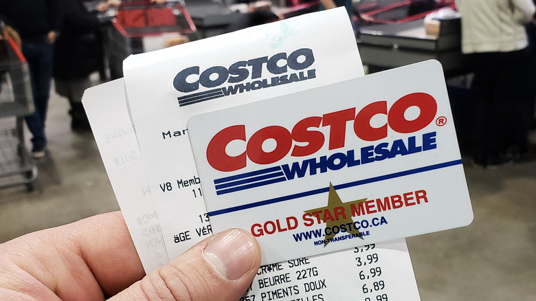 Hand holding Costco card and receipt