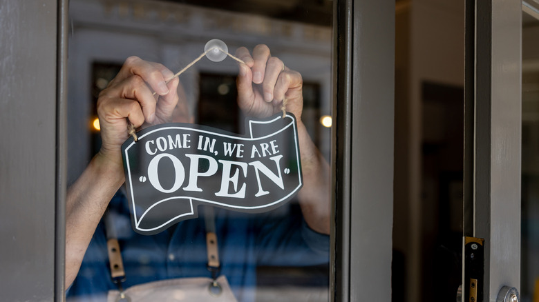 Business man hanging open sign