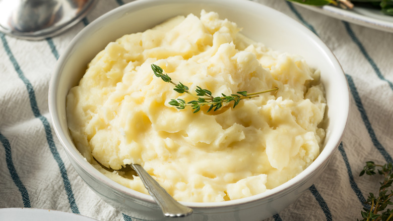 Mashed potatoes in a white bowl with a blue striped tablecloth underneath