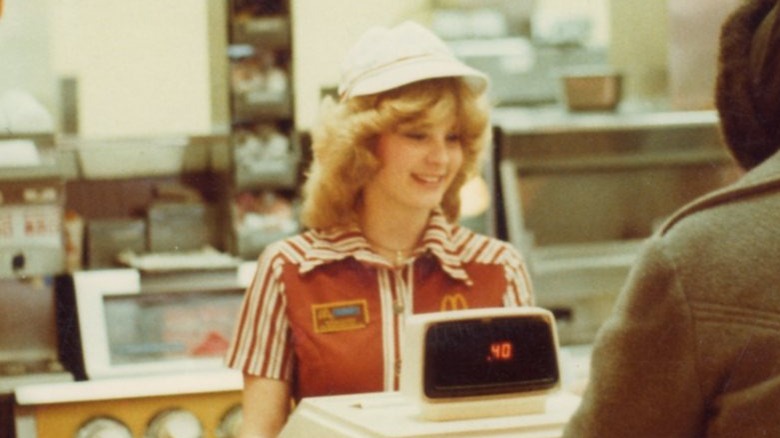 McDonald's cashier in a solid striped uniform helping a customer