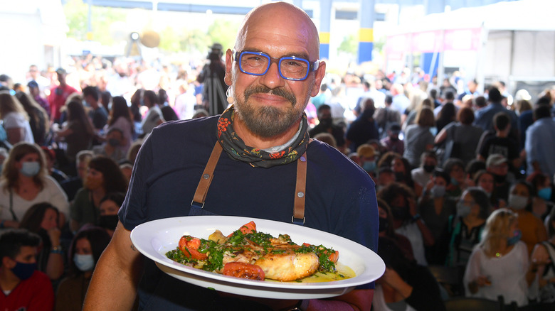 Chef Michael Symon serving food with blue glasses and shirt