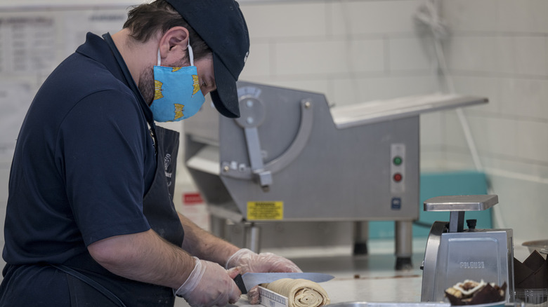 A Cinnabon employee slicing rolls