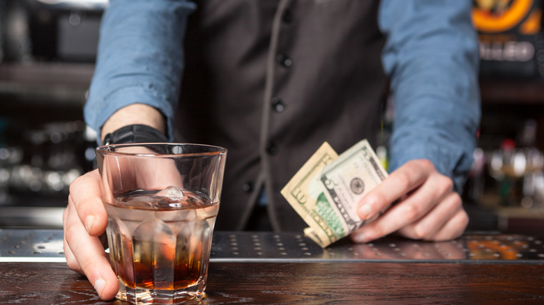 Beverage on bar with bartender taking tip