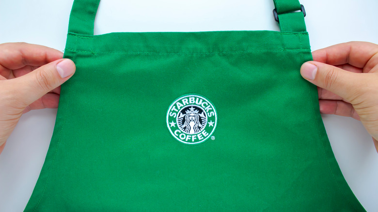 Person holding green Starbucks apron