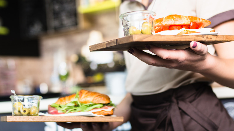 Waiter carrying sandwiches on wooden plates