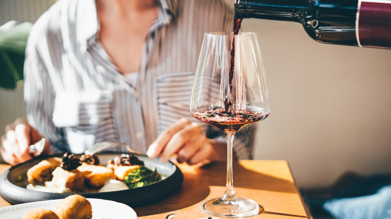 Pouring glass of red wine during a meal