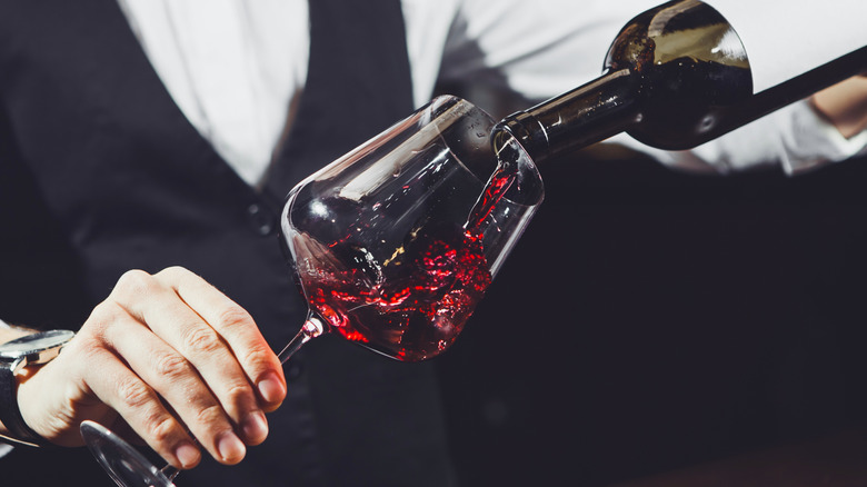 Restaurant server pouring red wine into glass