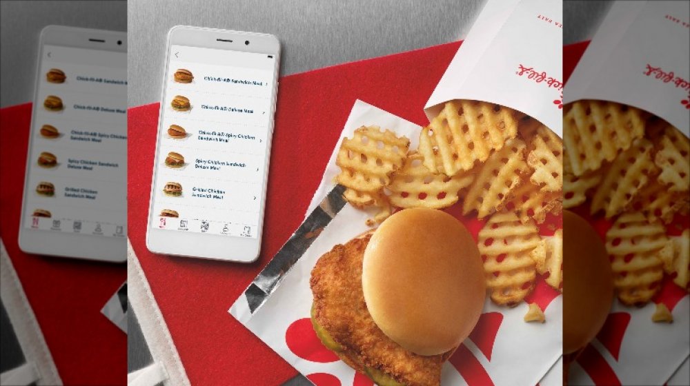 Chick-fil-A fried chicken sandwich and waffle fries with app open on phone