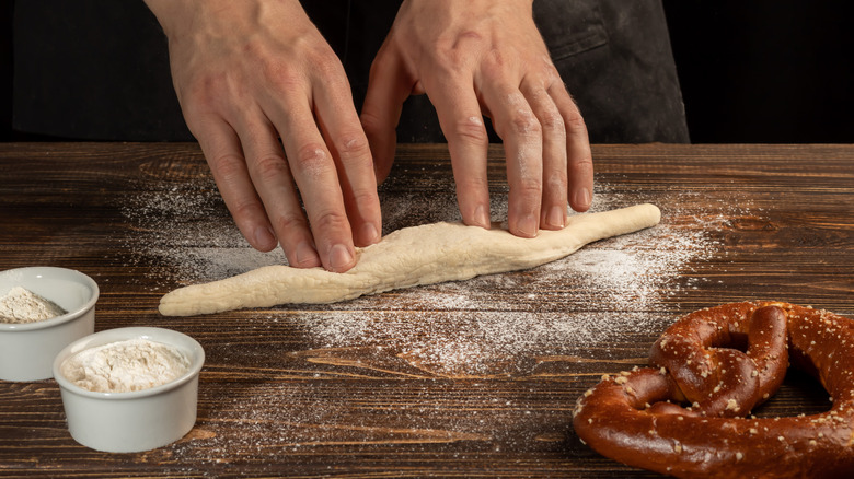 Hands shaping dough for a pretzel