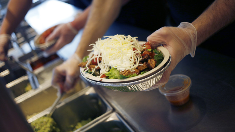 Chipotle worker making burrito bowl