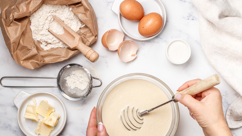 whisking together a batter with flour, butter, and brown eggs