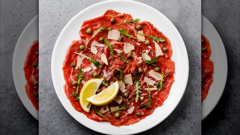 carpaccio on plate with salad greens and lemon