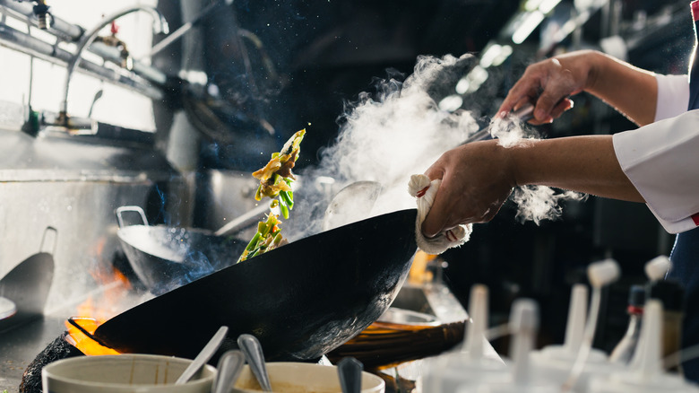 Person with black wok working in a kitchen