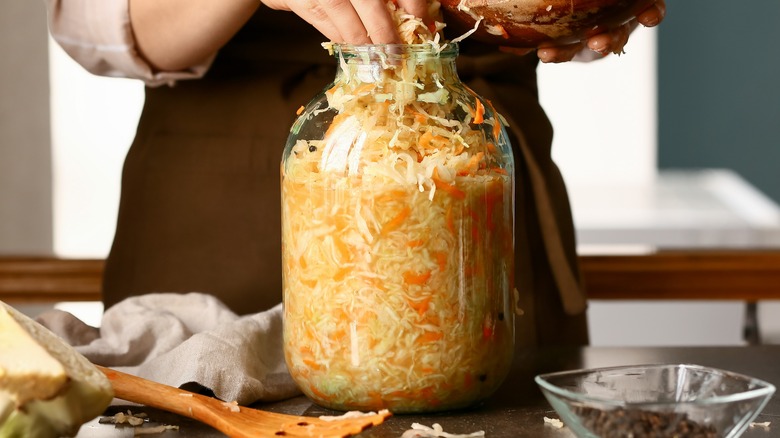 Hands stuffing sauerkraut into jar