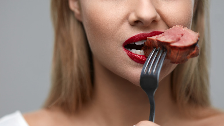 woman eating steak in lipstick