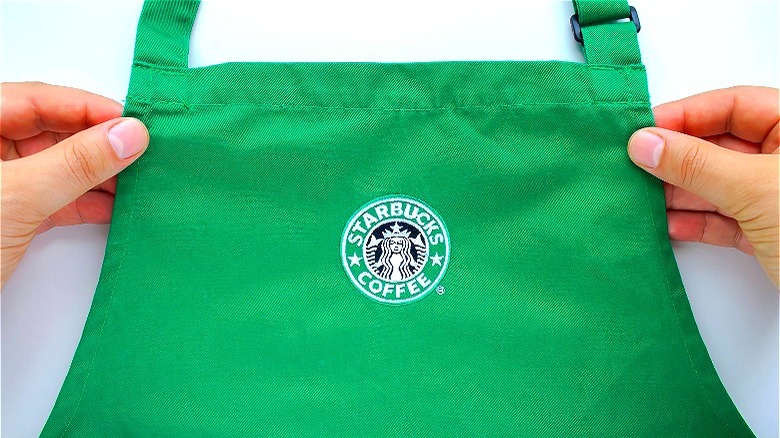 Hands holding green Starbucks apron