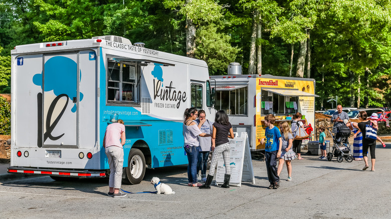 People eating at two food trucks