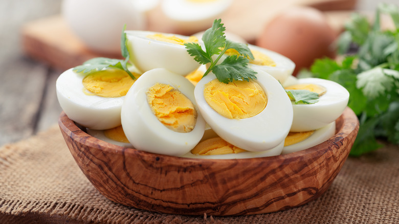 Hard-boiled eggs on wooden plate with herb garnish