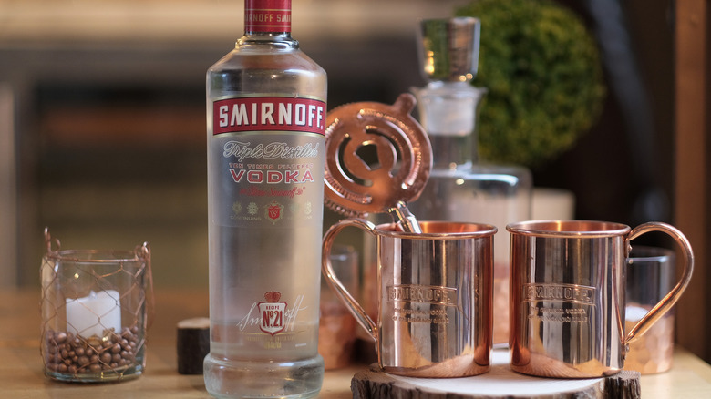 Smirnoff vodka bottle alongside Moscow Mule mugs